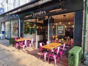 un restaurante con mesas rosas y sillas fuera de él en Creates, en Monmouth