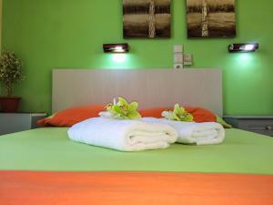 a green bedroom with a bed with towels and flowers at Athina Studios in Argasi