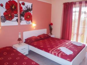 a bedroom with a bed with red sheets and a window at Athina Studios in Argasi
