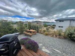 a picnic table on a wooden deck with purple flowers at Wayfarer Lodge Studio in Lake Tekapo