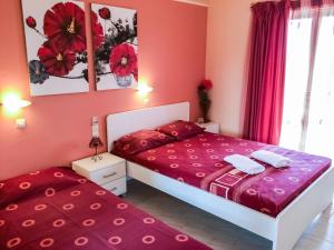 two beds in a room with pink walls at Athina Studios in Argasi