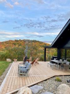 a wooden deck with chairs and a table on it at Balnea Hôtel - Anciennement Beatnik Hôtel in Bromont