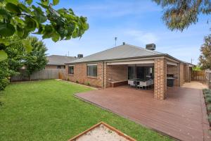 a brick house with a deck in the yard at Summer Breeze - 10 mins to Barwon Heads & Torquay! in Mount Duneed