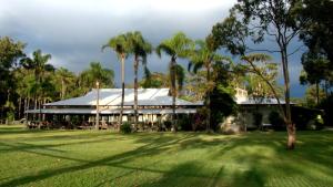 a building with palm trees in front of a yard at Valla Beach Holiday Park in Valla Beach