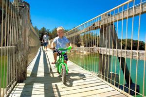 a young boy riding a bike across a bridge at Valla Beach Holiday Park in Valla Beach