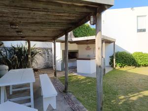 pérgola de madera con mesa blanca y sillas en un patio en Monoambiente en Montoya, en Punta del Este