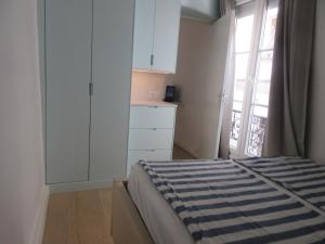 a bedroom with a bed and a kitchen with a window at Bourg-la-Reine : joli appartement de 20 m² in Bourg-la-Reine