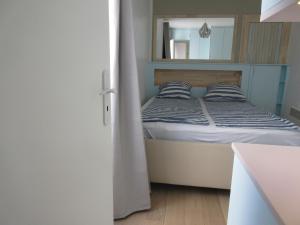 a small bedroom with a bed and a mirror at Bourg-la-Reine : joli appartement de 20 m² in Bourg-la-Reine