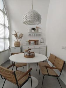 une cuisine avec une table et des chaises blanches ainsi qu'une lampe pendant dans l'établissement Nova Rua, à Amalfi