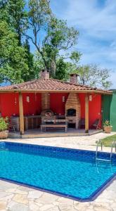 una casa roja con piscina frente a ella en Chalé dos Sonhos, en Ilhabela