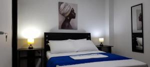 una camera da letto con un letto con una coperta blu e due lampade di La Marina -Apartamentos frente al mar a Ríohacha