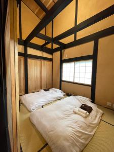 a bedroom with two beds with white sheets and a window at Kabuto Villas ー古民家ステイー 