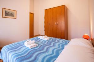 a bedroom with a blue and white bed with towels on it at Apartment Pasman 8274a in Pašman