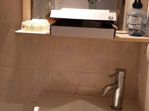 Un lavabo en un baño con un estante encima. en Gîte La Turballe, 1 pièce, 2 personnes - FR-1-306-901, en La Turballe