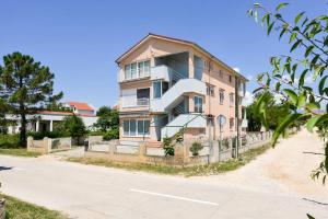 ein hohes Gebäude mit einem Zaun neben einer Straße in der Unterkunft Apartments with a parking space Vrsi - Mulo, Zadar - 13067 in Vrsi