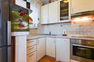 a kitchen with white cabinets and a duck picture on the wall at Apartments with a parking space Vrsi - Mulo, Zadar - 13067 in Vrsi