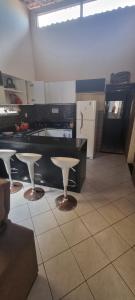 a kitchen with three stools and a black counter top at Casa com piscina no coração de Lucena in Lucena