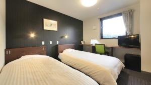 um quarto com 2 camas, uma secretária e uma janela em Hotel Coonel Inn em Susono