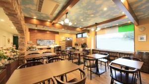um restaurante com mesas e cadeiras e um grande ecrã em Hotel Coonel Inn em Susono