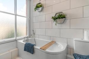 a white bathroom with a tub and a window at Boardman Lodge, City centre, Park view, Games - Ginger & Gold ltd in Norwich