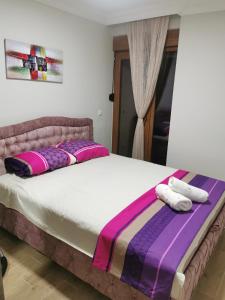 een slaapkamer met een groot bed met paarse en roze kussens bij Apartman DalMe in Novi Pazar