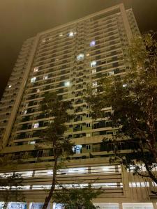 een groot appartementencomplex 's nachts met bomen op de voorgrond bij The Loop Condotel in Cagayan de Oro