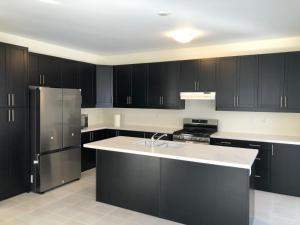 uma cozinha com armários pretos e um frigorífico de aço inoxidável em 537 Veterans Dr Brampton em Brampton