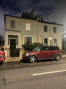 a red car parked in front of a house at London Cozy & Spacious Room 2 mins away from Train Station in London
