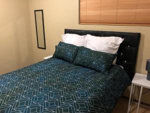 Schlafzimmer mit einem Bett mit einer blauen und weißen Bettdecke in der Unterkunft Q’s in Empangeni