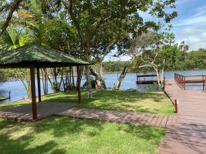 a wooden deck with a gazebo next to the water at Lençois Confort in Barreirinhas