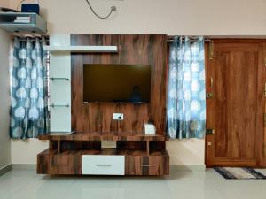 sala de estar con TV en una pared de madera en SV Serviced Apartments, en Chikmagalur