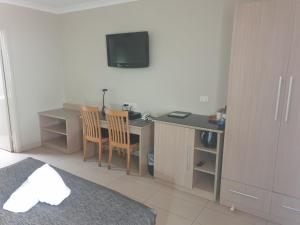a bedroom with a desk with a computer and a tv at Cobar Central Motor Inn in Cobar
