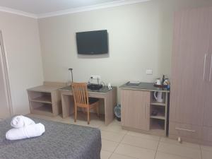 a bedroom with a desk and a bed and a desk with a chair at Cobar Central Motor Inn in Cobar