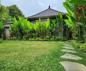 um jardim com um caminho em frente a uma casa em Pinggala Villa Ubud em Gianyar