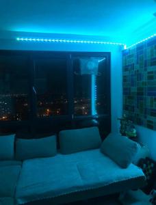 Habitación con sofá y ventana con luz azul. en Üniversite kapısında köy manzaralı daire, 