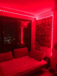 um quarto vermelho com um sofá e uma janela com luzes em Üniversite kapısında köy manzaralı daire 