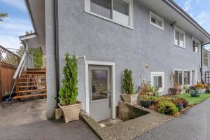 a gray house with potted plants in front of it at Quaint 1 bedroom lower suite in Victoria, BC in Victoria