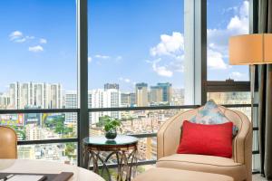 a chair with a red pillow in front of a large window at Wanda Vista Dongguan in Dongguan