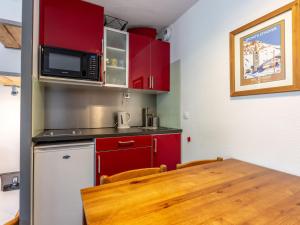 eine Küche mit roten Schränken und einem Holztisch in der Unterkunft Studio chaleureux à Val-d'Isère avec WIFI, animaux acceptés - FR-1-694-52 in Val dʼIsère