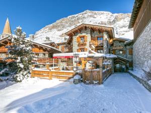 a log home in the snow in front of a mountain at Charmant Appartement Montagnard au Coeur du Vieux Village, aux Pieds des Pistes de Val-d'Isère - FR-1-694-77 in Val dʼIsère