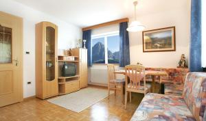 sala de estar con mesa, sofá y comedor en Apartments La Baita, en Santa Cristina Valgardena