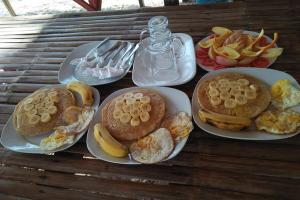 a table with three plates of breakfast foods and fruit at Tribe Banua 