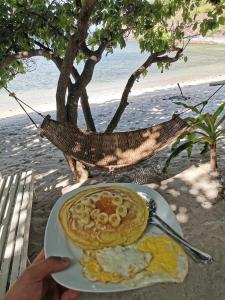 a plate of food with eggs and pancakes on the beach at Tribe Banua 