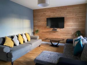 uma sala de estar com um sofá e uma televisão de ecrã plano em Birdwell For Contractors 