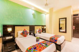 a hotel room with two beds and a mirror at FabHotel Atlas Plaza Andheri East in Mumbai