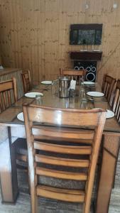una gran mesa de madera en una habitación con sillas en RRR RESORTS TIRTHAN Valley by RRR HOTELS & RESORTS en Banjār