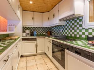 eine Küche mit weißen Schränken und grün-weiß karierten Fliesen in der Unterkunft Chalet rustique chaleureux avec cheminée à Val-d'Isère - FR-1-694-219 in Val dʼIsère + 10 Fotos