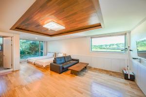 1 dormitorio con cama, sofá y ventana en Harmony Resort en Jeju