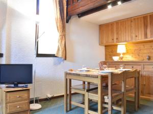 a kitchen with a table with chairs and a television at Appartement Méribel, 1 pièce, 4 personnes - FR-1-180-15 in Méribel