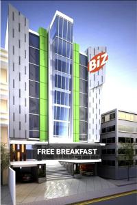 Deux grands bâtiments avec un panneau de petit-déjeuner gratuit devant eux dans l'établissement Biz Hotel Ambon, à Ambon